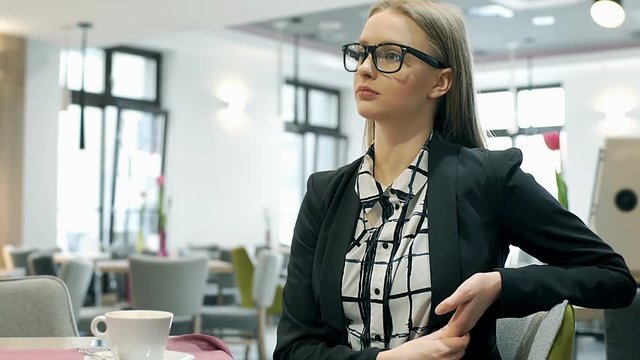 Elegant businesswoman in stylish clothes smiling to the camera in the cafe
