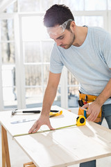 Mid-adult man marking table with measure tape