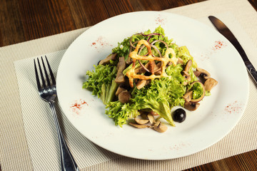 Salad with chicken, mushrooms and leaves of Iceberg lettuce and olives . Serving dishes in a restaurant, European cuisine, European restaurant, pub