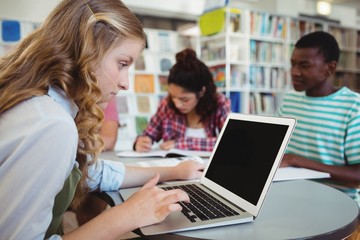 schoolgirl using laptop with her classmates