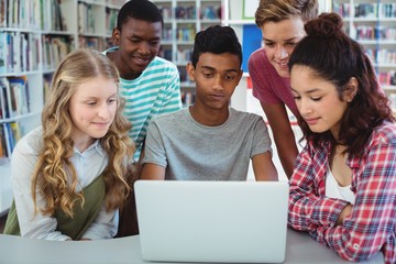 Attentive classmates using laptop in library