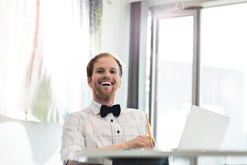 Fototapeta premium Cheerful businessman sitting at desk in creative office