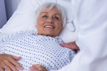 Mid-section of doctor consoling senior patient 