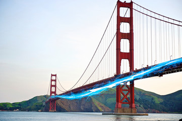 Blue streak of light passing by Golden Gate Bridge against clear sky