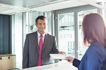 Businessman receiving document from receptionist in office