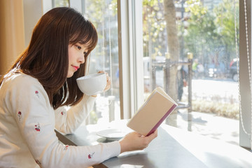 カフェで読書をする若い女性