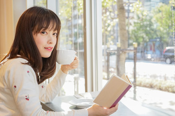 カフェで読書をする若い女性