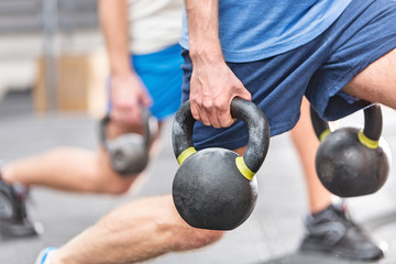 Fototapeta na wymiar Cropped image of men lifting kettlebells at crossfit gym