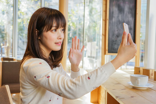 Young woman using phone at cafeteria