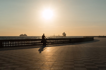 Silhouette of Woman Riding Bicycle on Livorno' s Mascagni Terrace, Tuscany, Italy