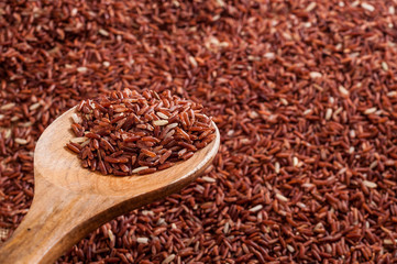 Wooden spoon with heap of brown raw rice