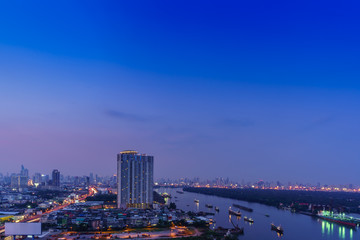 Cityscape of Bangkok in twilight viewing Rama III road along Chao Phraya river , Thailand