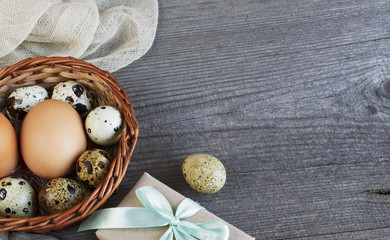Easter eggs in the basket on grey wooden table. Place for text.