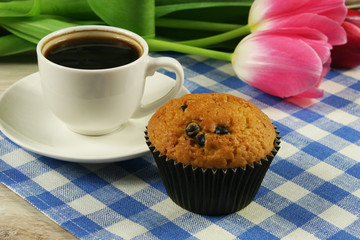 Chocolate muffins with a Cup of coffee and flowers on the table