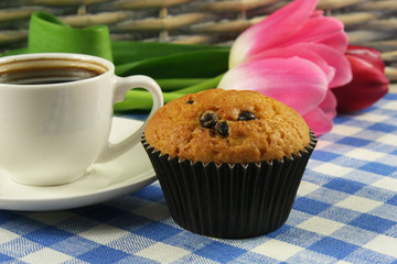 Chocolate muffins with a Cup of coffee and flowers on the table