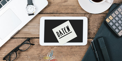 Naklejka premium Daten, German text for Data , yellow sticky note, office desk with computer technology, high angle