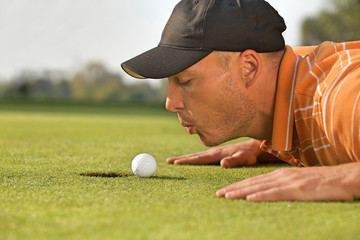 Close-up of man blowing on golf ball