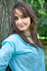 Fototapeta premium Portrait of young woman standing by tree and smiling