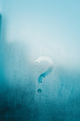 Question mark symbol on sunny foggy window glass blurry condensation background, closeup image....