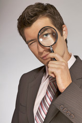 Fototapeta na wymiar Young caucasian businessman with magnifying glass