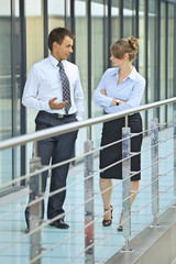 Businessman conversing with businesswoman at corridor