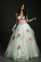 Fototapeta premium Bellissima modella in studio posa con vestito bianco da matrimonio con fiori 