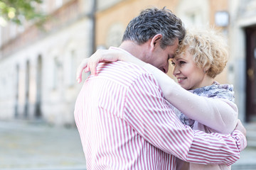 Happy middle-aged couple embracing in city