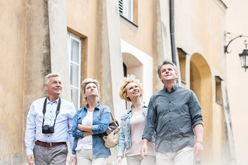 Smiling friends looking up while walking by building