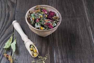 Herbal tea ingredients with hip roses, chamomile, herbs on wooden table