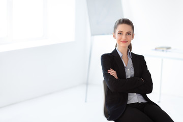 Portrait of young beautiful business woman sitting on chair in the office