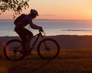 Fototapeta na wymiar Woman mountain biking on single track trail at Sunset