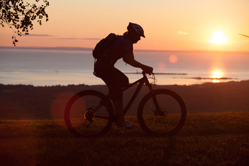 Fototapeta na wymiar Woman mountain biking on single track trail at Sunset
