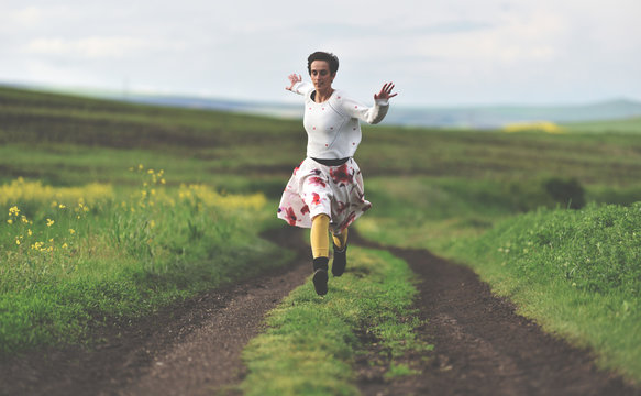Freedom concept. Cheerful girl running on a countryside road