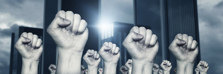 different raising up left fists in front of skyscraper and grey clouds