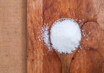 Fototapeta na wymiar Salt or sweet sugar in wooden spoon on wood desk