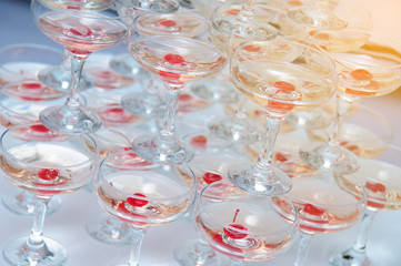 A pyramid of champagne glasses with a cherry