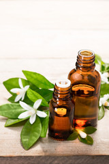 neroli essential oil in the brown glass bottle, with fresh white neroli flower and green leaves.