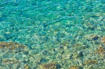 Rocky sea floor visible through crystal clear turqoise water of Aegean sea in Greece