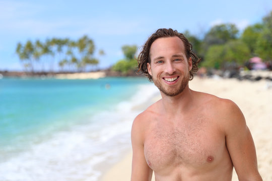 Handsome man on a tropical beach. Portrait of an attractive young male model topless on hawaiian travel destination.