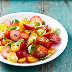 Colorful cherry tomato and strawberry salad with basil