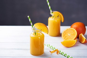 Fresh orange juice in the jar with straw on white wood table. Vertical shot