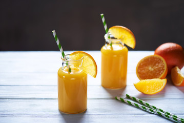 Fresh orange juice in the jar with straw on white wood table. Vertical shot