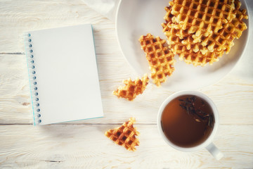 Cup of tea, waffle and notepad. Copyspace
