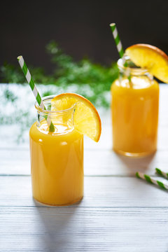 Fresh orange juice in the jar with straw on white wood table. Vertical shot