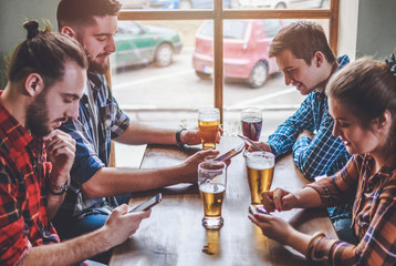 Social networking with glasses of beer in bar. Group Of Hipster Friends Drinking Beer