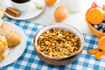 Granola, croissant, eggs, milk and fruits on a table. Healthy breakfast with coffee. International vegetarian meal. Top view.