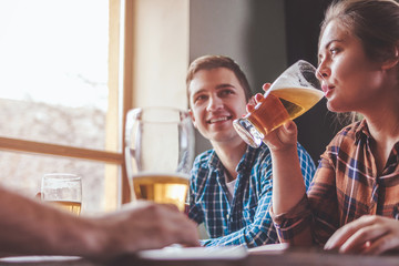 Hipster woman drinking beer with friends at bar or pub
