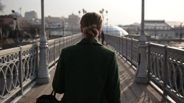 Back view of woman walking away on bridge