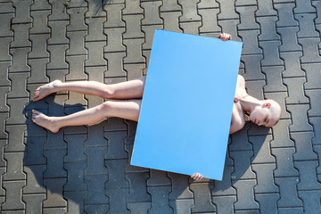 Young naked woman is lying on the road.