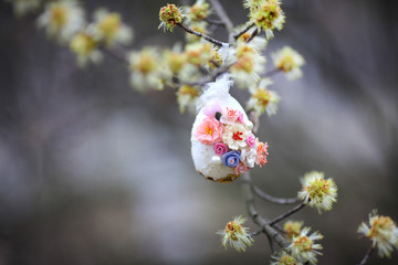 Decorative easter egg. An egg on a tree branch. Flowers blossom on the tree